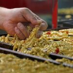 A salesman holds gold to sell to a customer at a gold shop in Bangkok's Chinatown