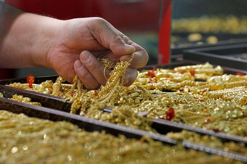 A salesman holds gold to sell to a customer at a gold shop in Bangkok's Chinatown