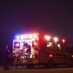 Paramedics carrying patient in ambulance at night